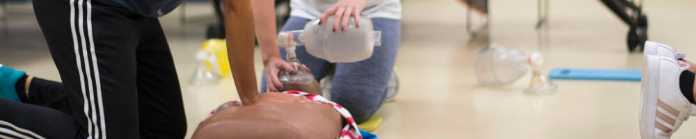 Two students perform a respiratory technique on a medical manikin